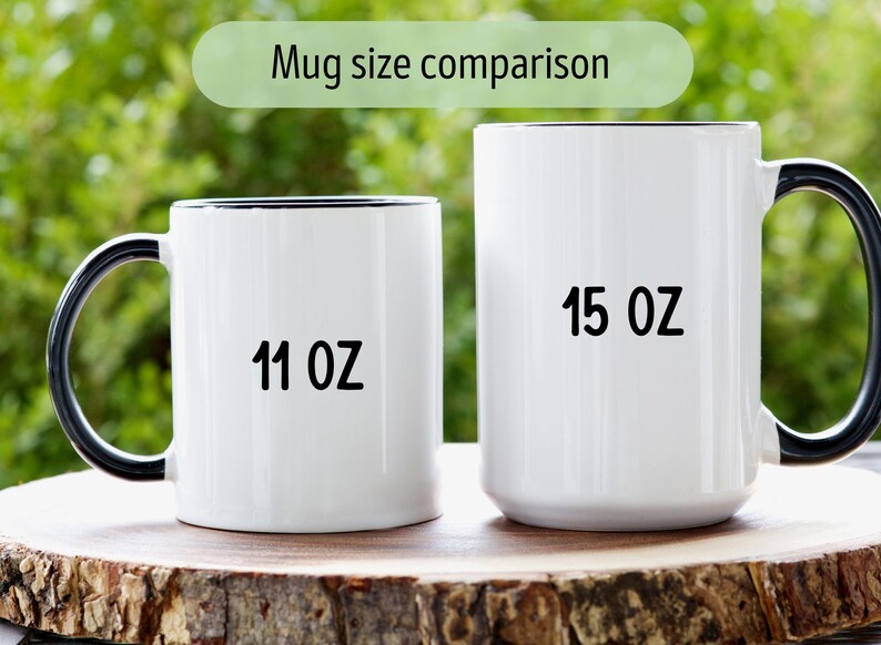 Op de afbeelding: Zij-aan-zij vergelijking van twee witte keramische mokken met zwarte randen en handvatten. De mok aan de linkerkant is 11 oz en de mok aan de rechterkant is 15 oz.