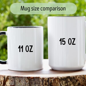 Peut inclure: Deux mugs en c&eacute;ramique blanche avec des bords et des anses noirs sont pr&eacute;sent&eacute;s sur une surface en bois. Les tasses sont &eacute;tiquet&eacute;es "11 OZ" et "15 OZ" en texte noir, indiquant leurs tailles. L'arri&egrave;re-plan est un feuillage vert flou.