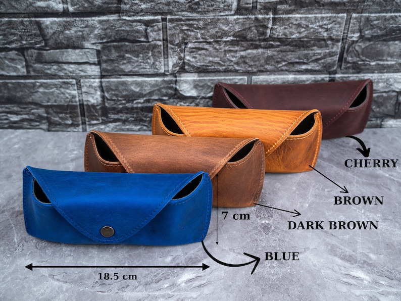 May include: Four leather eyeglass cases in blue, brown, dark brown, and cherry. The blue case is 7 cm high and 18.5 cm long. Each case features a snap closure and a curved design.