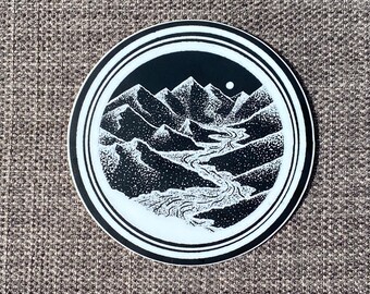 May include: Black and white sticker with a circular design featuring a stylized mountain range with a winding river flowing through it. A small moon is visible in the sky above the mountains.