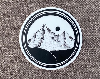 May include: Black and white sticker with a stylized illustration of a mountain range with a sun in the background.
