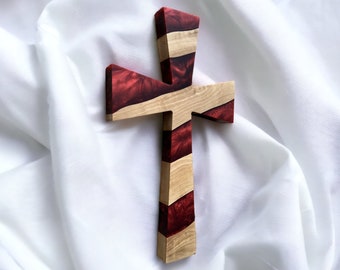 May include: A wooden cross with red and brown resin inlay. The cross is a decorative wall hanging.