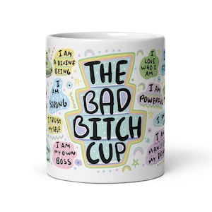 Peut inclure: Une tasse en céramique blanche avec un motif coloré comportant le texte "The Bad Bitch Cup". Le motif comprend diverses affirmations telles que "Je suis forte", "J'ai confiance en moi", "Je suis mon propre patron", "J'aime qui je suis", "Je suis puissante" et "Je manifeste mes rêves".