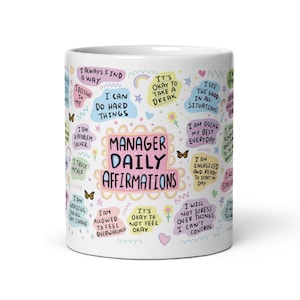 May include: White ceramic mug with colorful text and illustrations. The text includes affirmations for managers, such as "I always find a way", "I can do hard things", "It's okay to take a break", "I see the good in all situations", "I am doing my best everyday", "I am energized and ready to start my day", "I will not stress over things I can't control", "I am grateful for all that I have", "I am allowed to feel overwhelmed okay", and "It's okay to not feel okay".