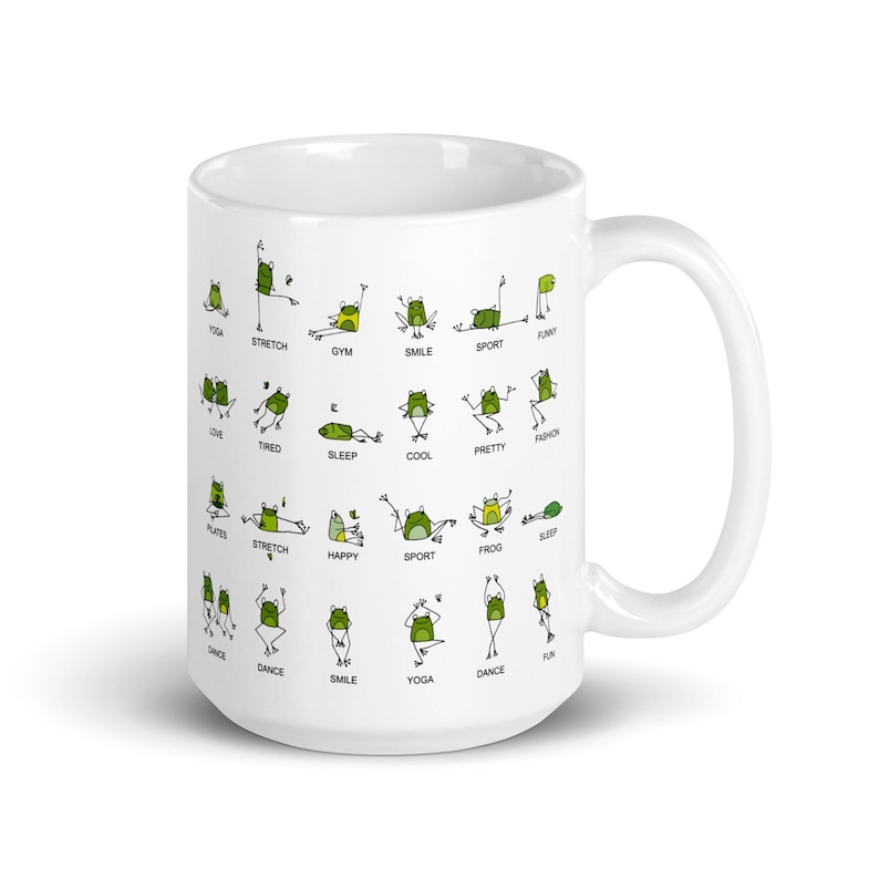May include: White ceramic mug featuring green frog illustrations in various yoga poses, with words like "Yoga", "Stretch", and "Smile". The mug has a curved handle and a glossy finish.