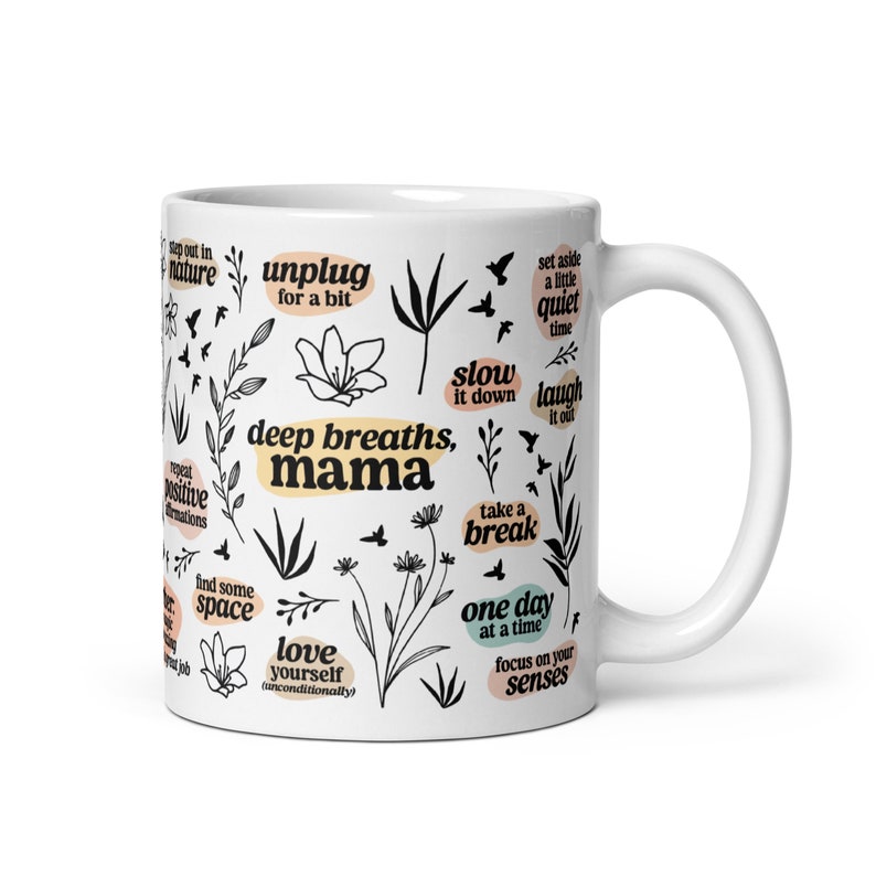 May include: White ceramic mug with black and beige botanical illustrations and phrases like "deep breaths, mama" and "one day at a time." The mug features a curved handle and is designed for hot beverages.