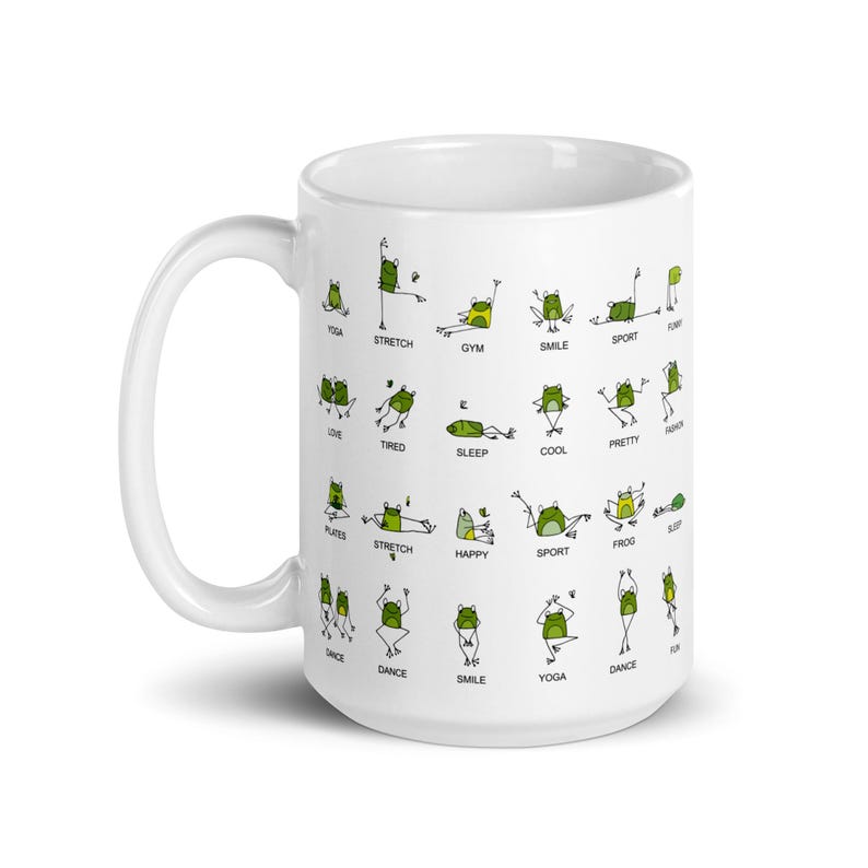 May include: White ceramic mug featuring green cartoon frogs in various yoga poses, with words like "stretch", "smile", and "yoga". The mug has a large handle and is suitable for hot or cold beverages.