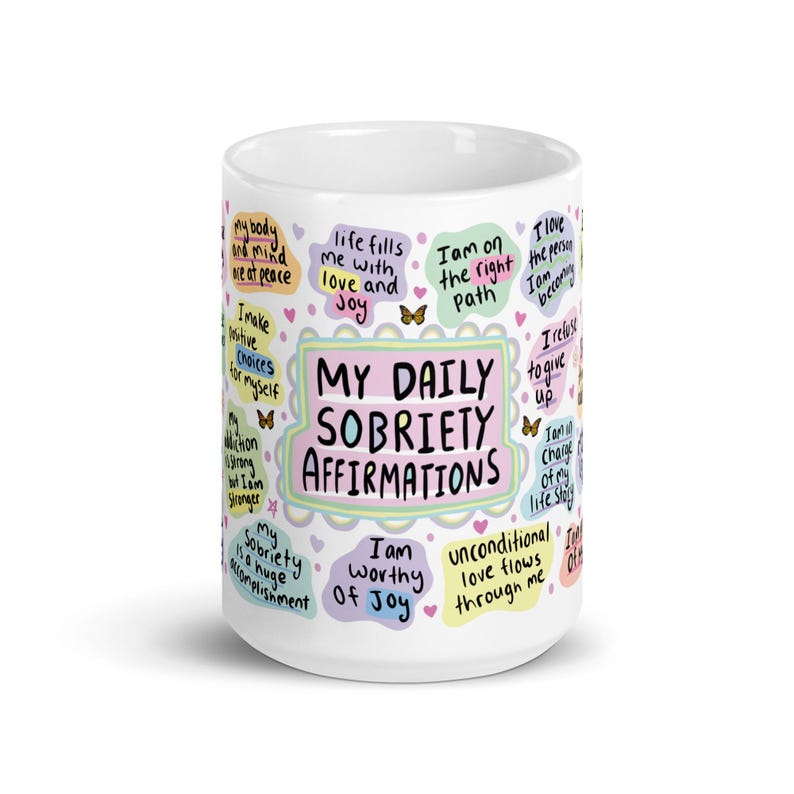 May include: White ceramic mug with colourful text and illustrations. The text reads "My Daily Sobriety Affirmations" and includes phrases like "I am worthy of joy" and "Life fills me with love and joy".