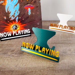 May include: Three "Now Playing" signs, one white, one green, and one black with white lettering. The signs are made of plastic and have a gold accent.