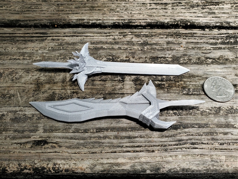 Small but detailed 3D printed swords based on designs from a video game sit next to a quarter to demonstrate their size. Similar custom 3D printing projects can be commissioned from the Nautolith Crafts shop.