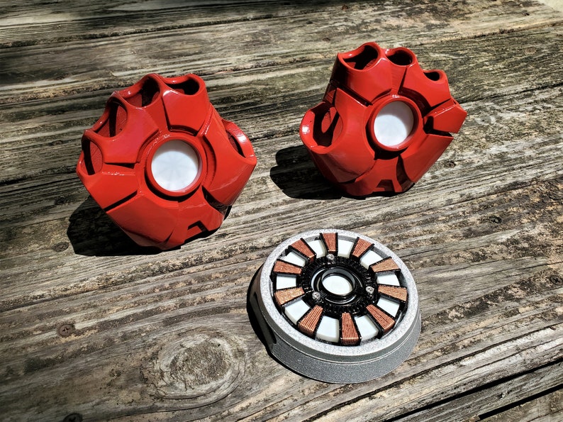 A pair of red robotic fingerless gloves and an electronic chest piece based on pieces of a superhero's suit provide examples of custom 3D printed cosplay pieces produced by the shop Nautolith Crafts.