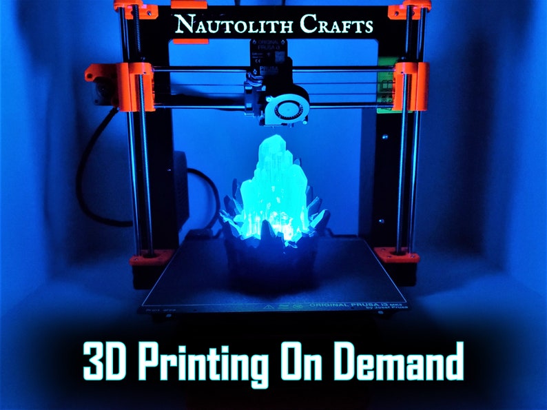 An illuminated 3D printed blue crystal LED lamp sits on the build plate of a 3D printer. The text "3D Printing on Demand" indicates that this listing offers personalize custom 3D printing services from the shop Nautolith Crafts.