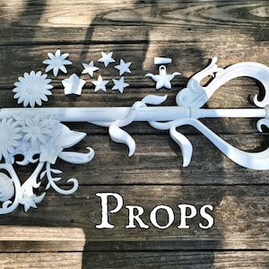 The text "Props" below a large ornate key adorned with vines and flowers based on an item from a video game. An example of a large cosplay prop commissioned from the shop Nautolith Crafts.
