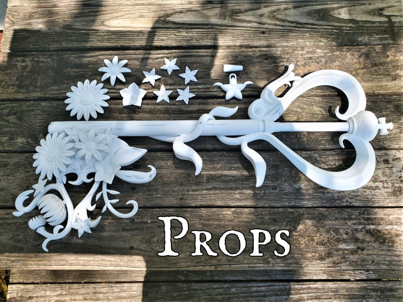 The text "Props" below a large ornate key adorned with vines and flowers based on an item from a video game. An example of a large cosplay prop commissioned from the shop Nautolith Crafts.