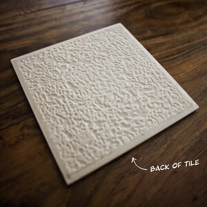 May include: The back of a white ceramic tile with a textured surface. The tile is rectangular and has a rough, uneven texture. The text "BACK OF TILE" is written on the bottom right corner of the tile.