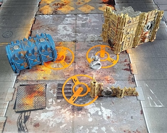 May include: A tabletop gaming scene featuring miniature terrain pieces. Includes a blue cylindrical structure, a tan building facade, and orange circular elements. A small silver figurine is also present, all set on a textured, industrial-themed game board.
