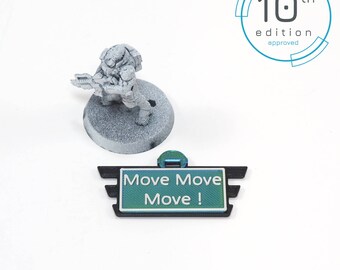 May include: A green and white sign with the text "Move Move Move!" printed on it. The sign is attached to a black plastic base with a wing design. The sign is 10th edition approved.