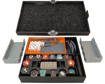 May include: A black organizer with orange and gray inserts for storing dice, tokens, and other game components. The organizer is open and shows the contents, including dice, tokens, and a pen.