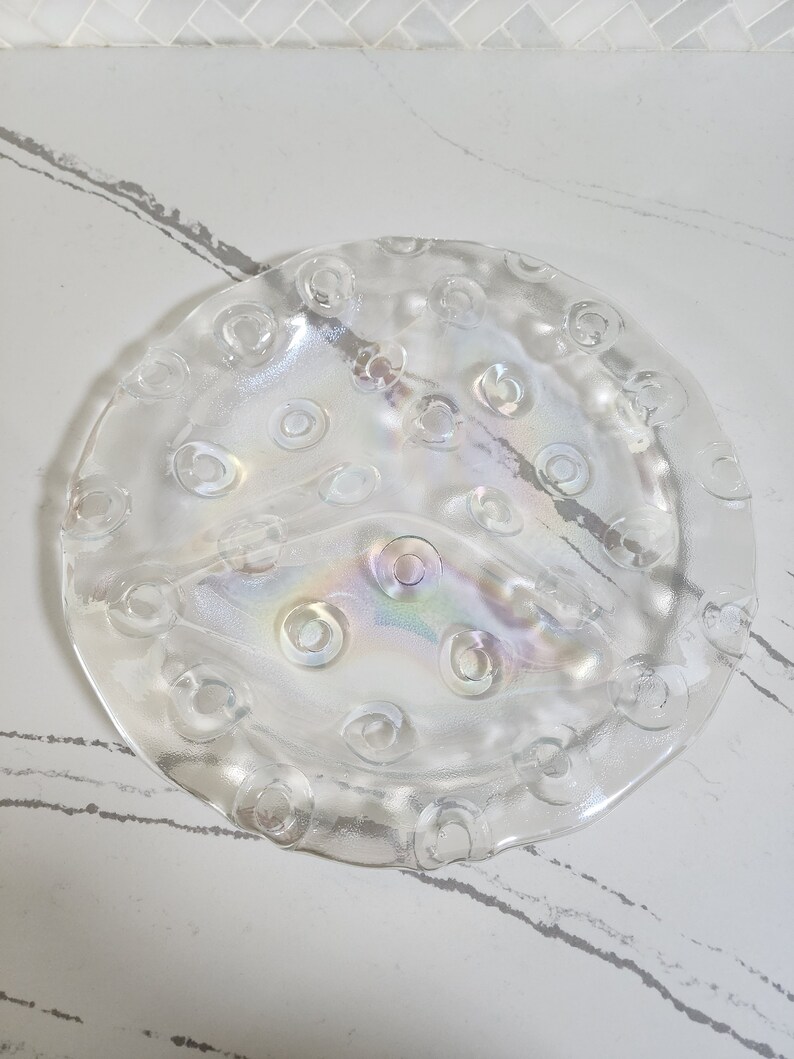 May include: A clear glass serving dish with a raised, textured rim and a scalloped edge. The dish has a iridescent finish and is divided into three sections.