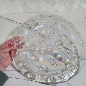 May include: A clear glass serving dish with a raised, textured design of circles. The dish has three sections and a slightly iridescent finish.