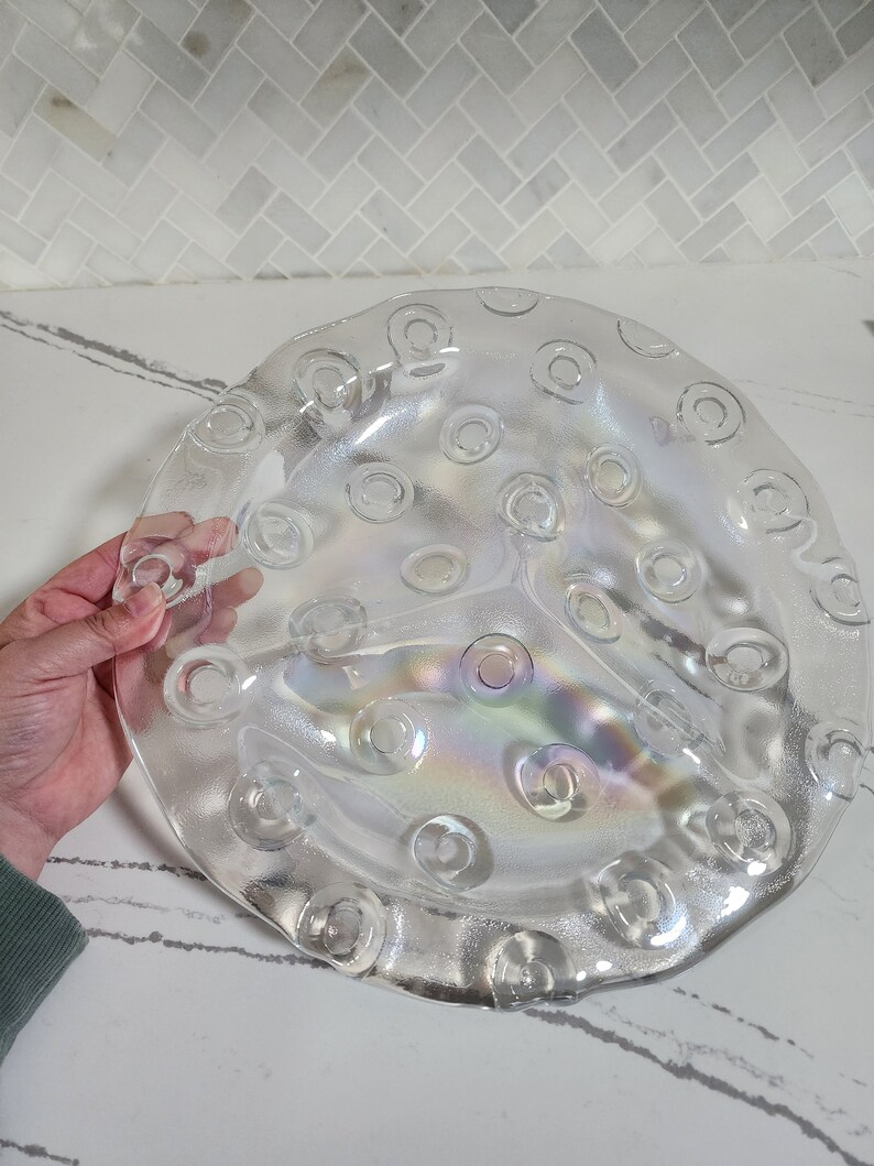 May include: A clear glass serving dish with a raised, textured design of circles. The dish has three sections and a slightly iridescent finish.