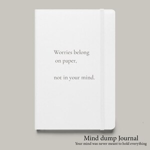 May include: A white journal with the text "Worries belong on paper, not in your mind." A matching elastic band secures the journal. The words "Mind dump Journal" and "Your mind was never meant to hold everything" are at the bottom.