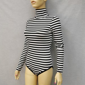 Peut inclure: Combinaison à manches longues rayée noir et blanc avec un col roulé.