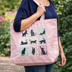 May include: A pink tote bag featuring black cat silhouettes on a patchwork design. The bag has a rectangular shape with a large capacity and long straps for carrying over the shoulder. The patchwork includes floral and solid color squares.