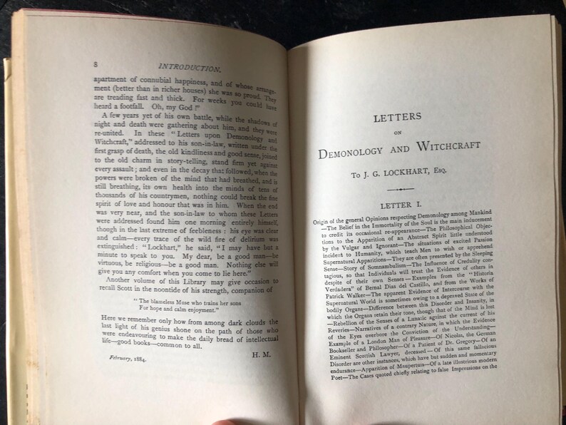 Op de afbeelding: Open boek met de titel "Letters on Demonology and Witchcraft" van J.G. Lockhart. De pagina's zijn vergeeld, wat duidt op ouderdom, met tekst in een klassiek schreeflettertype. Het boek is waarschijnlijk antiek, met focus op historische teksten.