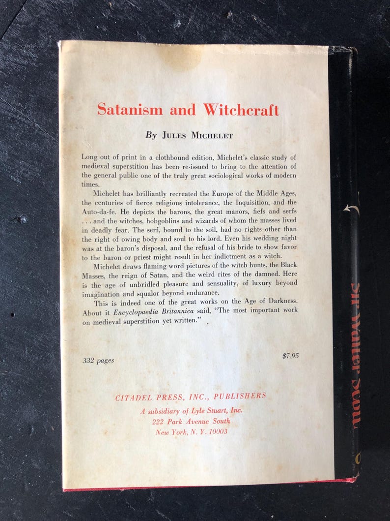 Op de afbeelding: De achterkant van een boek getiteld "Satanism and Witchcraft" van Jules Michelet. De omslag is gebroken wit met zwarte tekst en een zwarte rug. De tekst beschrijft de focus van het boek op middeleeuws bijgeloof en de Age of Darkness.