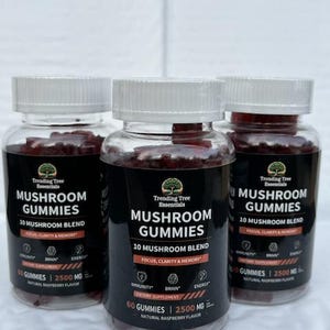 May include: Three bottles of mushroom gummies with white lids. The labels read "Mushroom Gummies" and "10 Mushroom Blend" with icons for immunity, brain, and energy. The gummies are a reddish-purple colour. The bottles are made of clear glass.