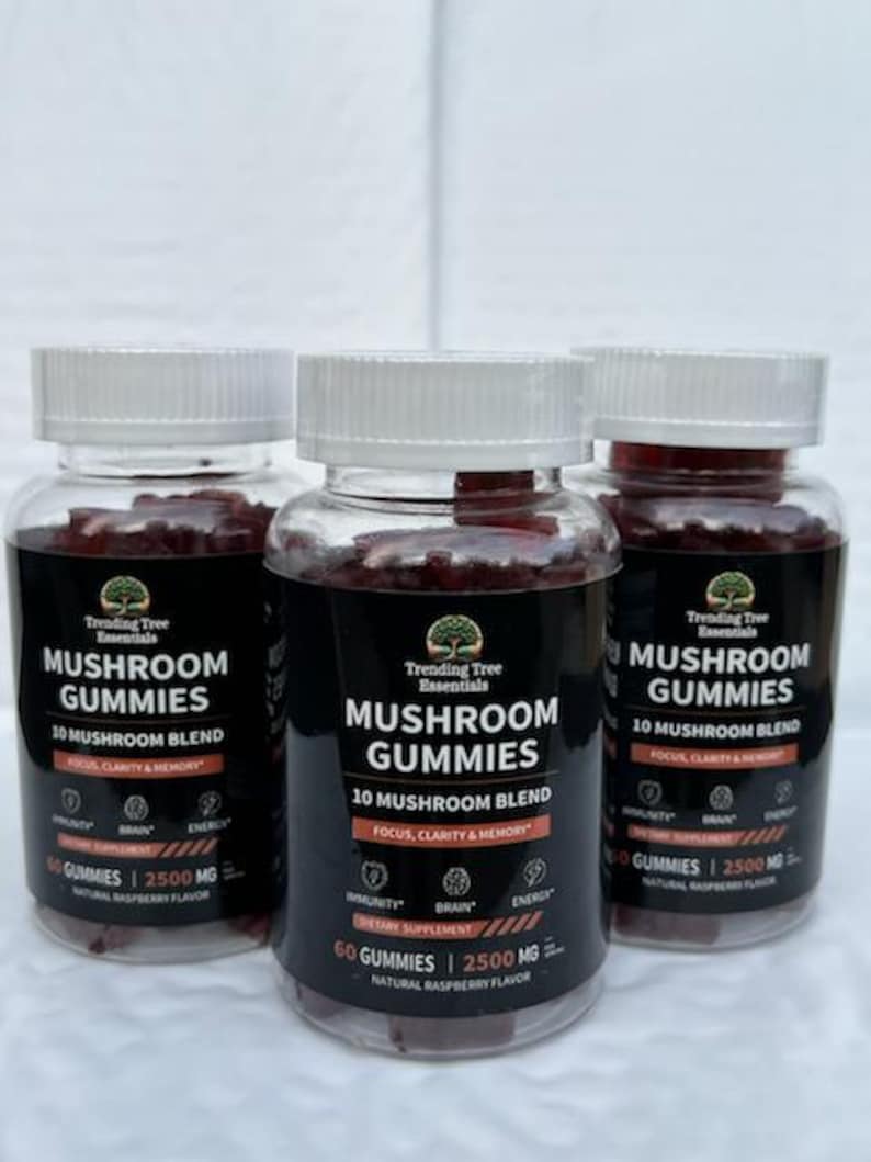 May include: Three bottles of mushroom gummies with white lids. The labels read "Mushroom Gummies" and "10 Mushroom Blend" with icons for immunity, brain, and energy. The gummies are a reddish-purple colour. The bottles are made of clear glass.
