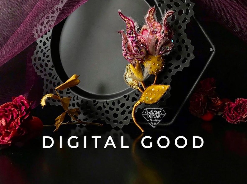 K&ouml;nnte beinhalten: Eine zarte, handgefertigte Blumenbrosche mit einer rosa und violetten Bl&uuml;te und goldenen Bl&auml;ttern. Die Brosche wird auf einer schwarzen Spitzendoily mit dem Text "DIGITAL GOOD" und "OKSANA KONAK" darunter pr&auml;sentiert.