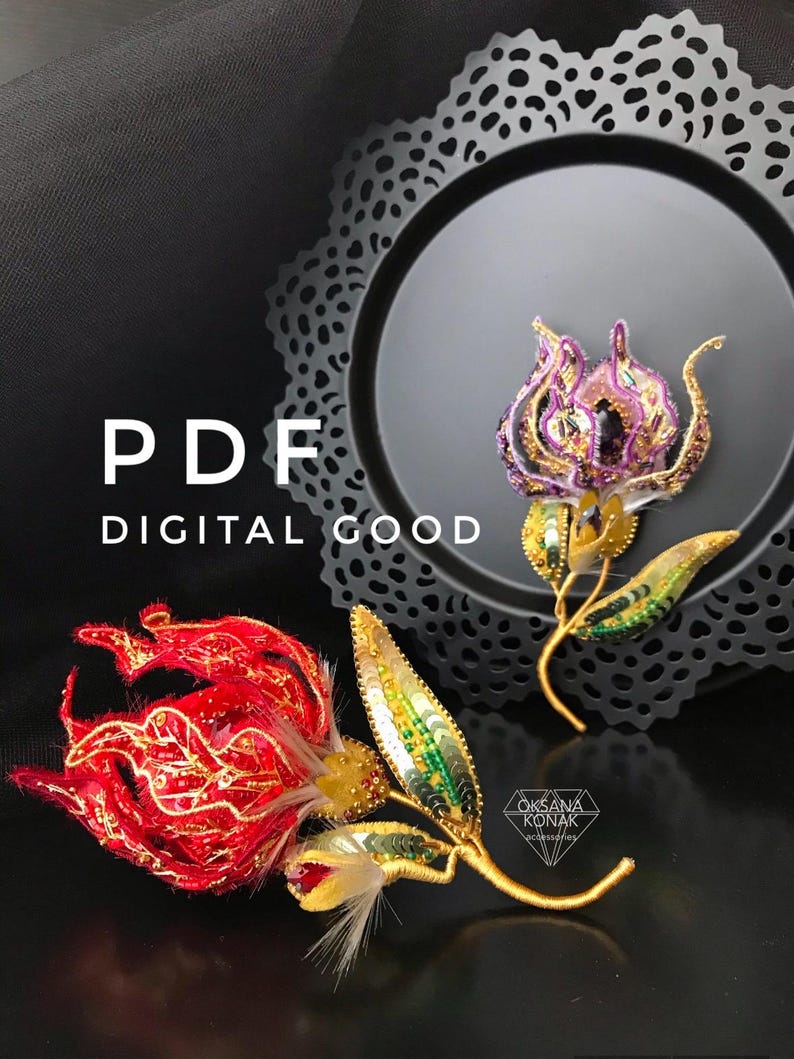 K&ouml;nnte beinhalten: Zwei gestickte Blumenbroschen, eine rote und eine violette, mit goldenen Akzenten und gr&uuml;nen Pailletten. Die Broschen werden auf einem schwarzen Hintergrund mit einer dekorativen Spitzenborte pr&auml;sentiert.