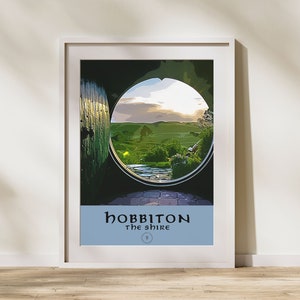 Peut inclure: Une affiche encadrée avec une porte verte et une fenêtre ronde donnant sur un champ vert. L'affiche porte le texte "Hobbiton The Shire" en bas.