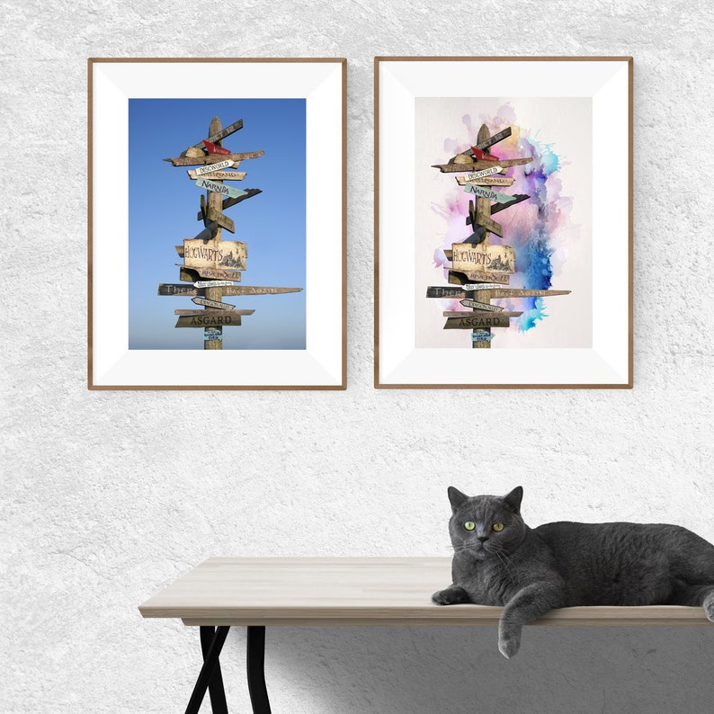 May include: Two framed prints of a wooden signpost with multiple arrows pointing in different directions. The signpost has handwritten signs with various destinations, including Hogwarts, Neverland, and Asgard. The print on the left has a blue sky background, while the print on the right has a watercolour background with pink, blue, and purple hues.