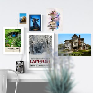 May include: A collection of six vintage travel posters featuring various destinations, including Hobbiton, Toad Hall, Lamp-Post, and a snowy forest. The posters are framed and displayed on a white wall.