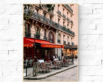 May include: A Parisian cafe with a red awning that says "Les Deux Compères". The cafe has tables and chairs set up outside on a cobbled street.