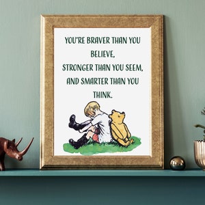 Puede incluir: Una impresión enmarcada con una ilustración de acuarela de un niño y un oso de peluche. El texto dice "Eres más valiente de lo que crees, más fuerte de lo que pareces, y más inteligente de lo que piensas."