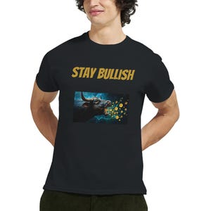 Può includere: T-shirt nera con la scritta "STAY BULLISH" in lettere dorate. La maglietta presenta un'immagine di un toro che espira monete d'oro, su uno sfondo di fulmini blu e bianchi.