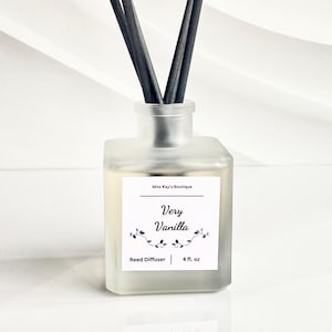May include: A frosted glass reed diffuser with black reeds. The label reads "Very Vanilla" with floral accents and "4 fl. oz." The product is from "Miss Kay's Boutique".