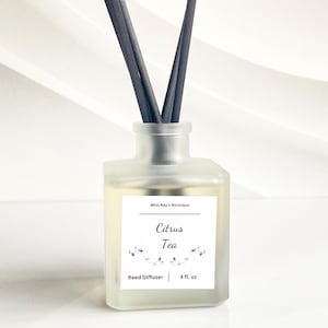 Könnte beinhalten: Ein Diffusor aus mattiertem Glas mit schwarzen Stäbchen. Das Etikett lautet "Citrus Tea" mit floralen Akzenten. Die Flasche enthält 118 ml Flüssigkeit. Das Produkt stammt von Miss Kay's Boutique.