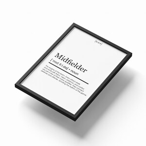 Puede incluir: Un marco negro con una impresión que define el término "Midfielder". El texto negro sobre fondo blanco incluye la pronunciación fonética y una descripción del rol en un equipo de fútbol.