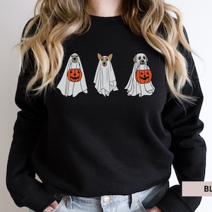 Peut inclure: Sweat-shirt noir avec un motif de trois chiens habill&eacute;s en fant&ocirc;mes tenant des citrouilles. Le texte "BLACK" est visible dans le coin inf&eacute;rieur droit de l'image.