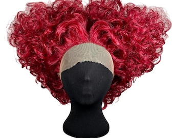 May include: A vibrant red curly wig styled on a black mannequin head. The wig features a lace front and a voluminous, heart-shaped silhouette. The curls are tightly wound and create a full, textured look.