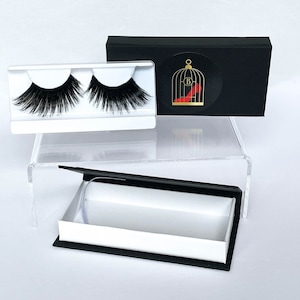 May include: A pair of black false eyelashes in a white plastic case with a black and white box with a logo of a birdcage with a red high heel shoe inside.
