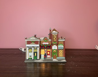 May include: A miniature village scene with three buildings, a red brick bank with the words "National Bank", a barber shop with the word "Barber" and a shop with the words "Specialty Shop".