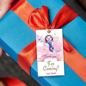 Puede incluir: Una etiqueta de agradecimiento rosa y blanca con un personaje de dibujos animados de una ni&ntilde;a ara&ntilde;a. La etiqueta tiene un fondo de acuarela rosa con un borde blanco y el texto "&iexcl;Gracias por venir! Con cari&ntilde;o, Claudia".