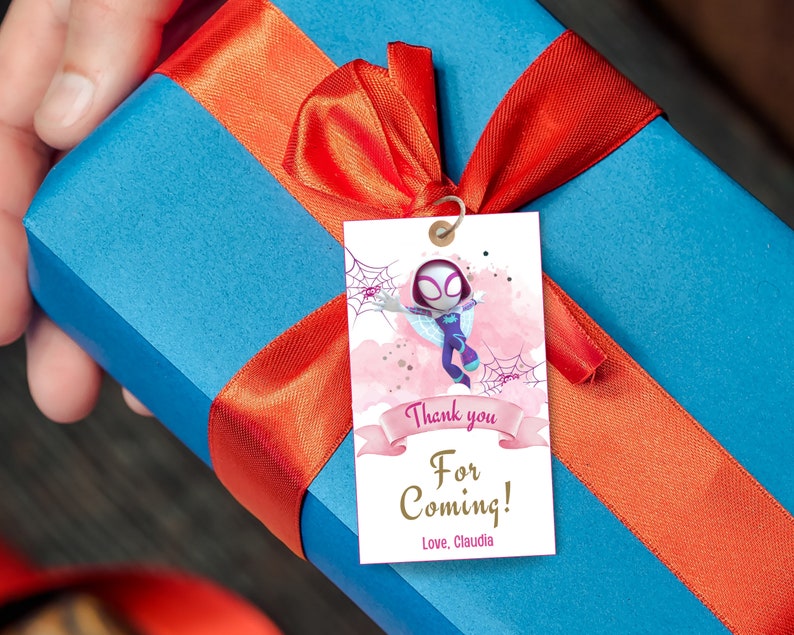 Puede incluir: Una etiqueta de agradecimiento rosa y blanca con un personaje de dibujos animados de una ni&ntilde;a ara&ntilde;a. La etiqueta tiene un fondo de acuarela rosa con un borde blanco y el texto "&iexcl;Gracias por venir! Con cari&ntilde;o, Claudia".