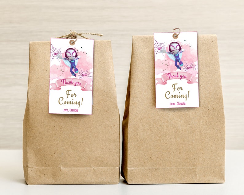 Puede incluir: Dos bolsas de papel marr&oacute;n con etiquetas de agradecimiento rosa y blancas adjuntas. Las etiquetas presentan una imagen de dibujos animados de una ni&ntilde;a vestida como Spider-Man. El texto en las etiquetas dice "&iexcl;Gracias por venir! Con cari&ntilde;o, Claudia."